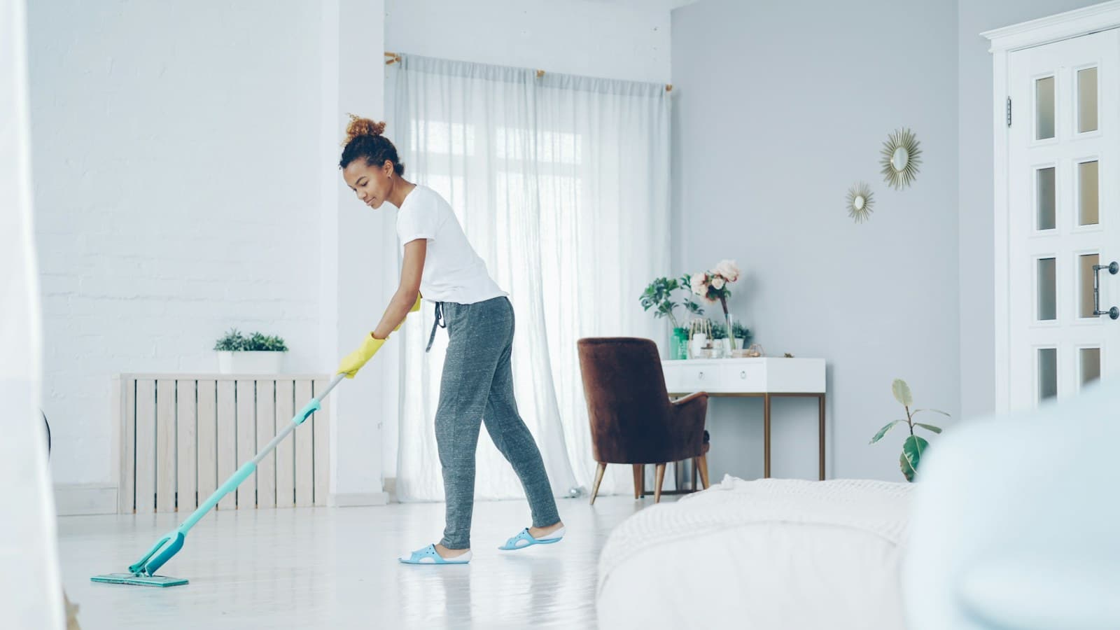 A woman mops a bright living room, preparing the home for guests